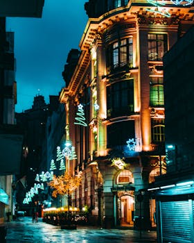 一条充满活力的夜间城市街道，明亮的建筑和节日灯光营造出喜怒无常的城市氛围