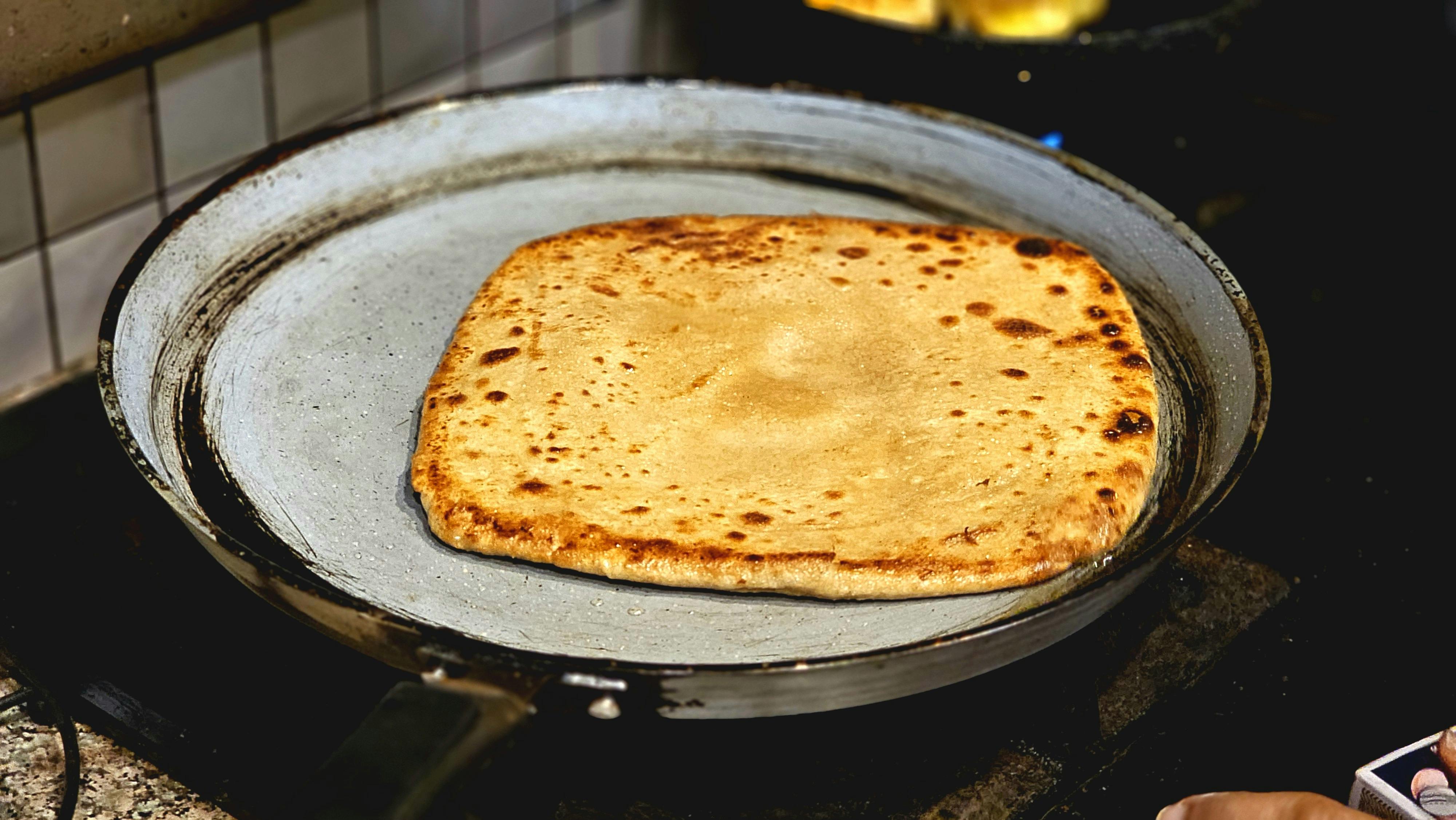 Close-up of a freshly cooked chapati on a skillet, highlighting traditional cooking.