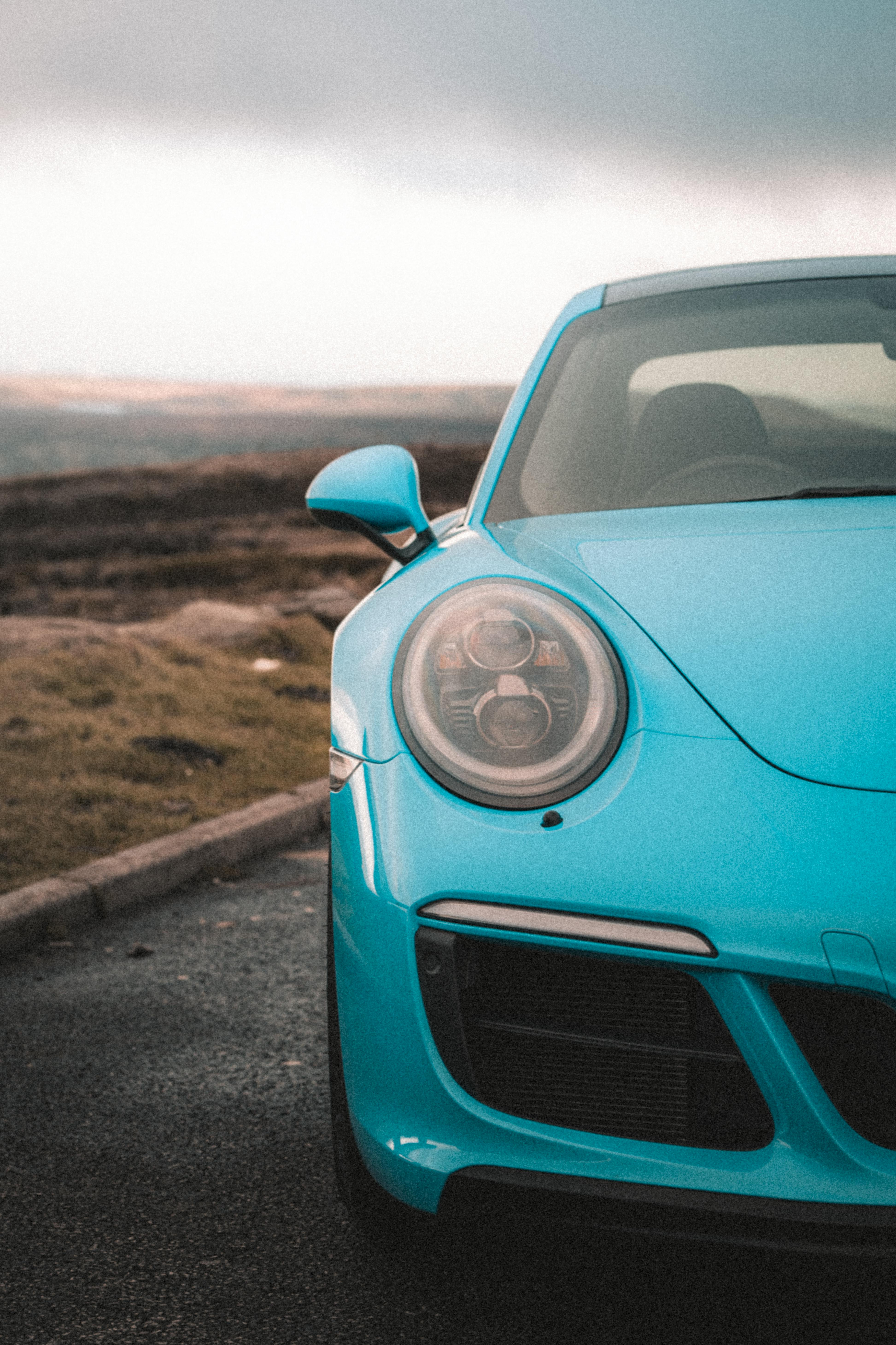 Free Dynamic shot capturing a blue sports car on an open road with Manchester's countryside backdrop. Stock Photo