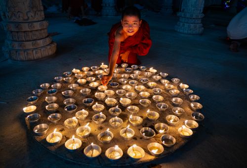 Free A young monk lights candles in a serene Chattogram temple setting, embracing Buddhist traditions. Stock Photo