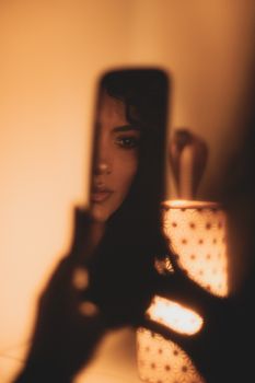 Artistic reflection of a woman in a mirror with warm, soft lighting, creating a moody ambience.