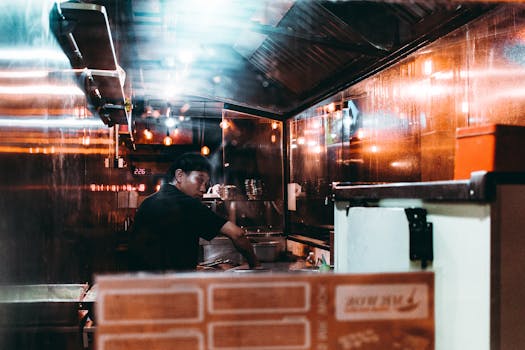 Asian chef focused on cooking in a modern, moody urban kitchen at night.