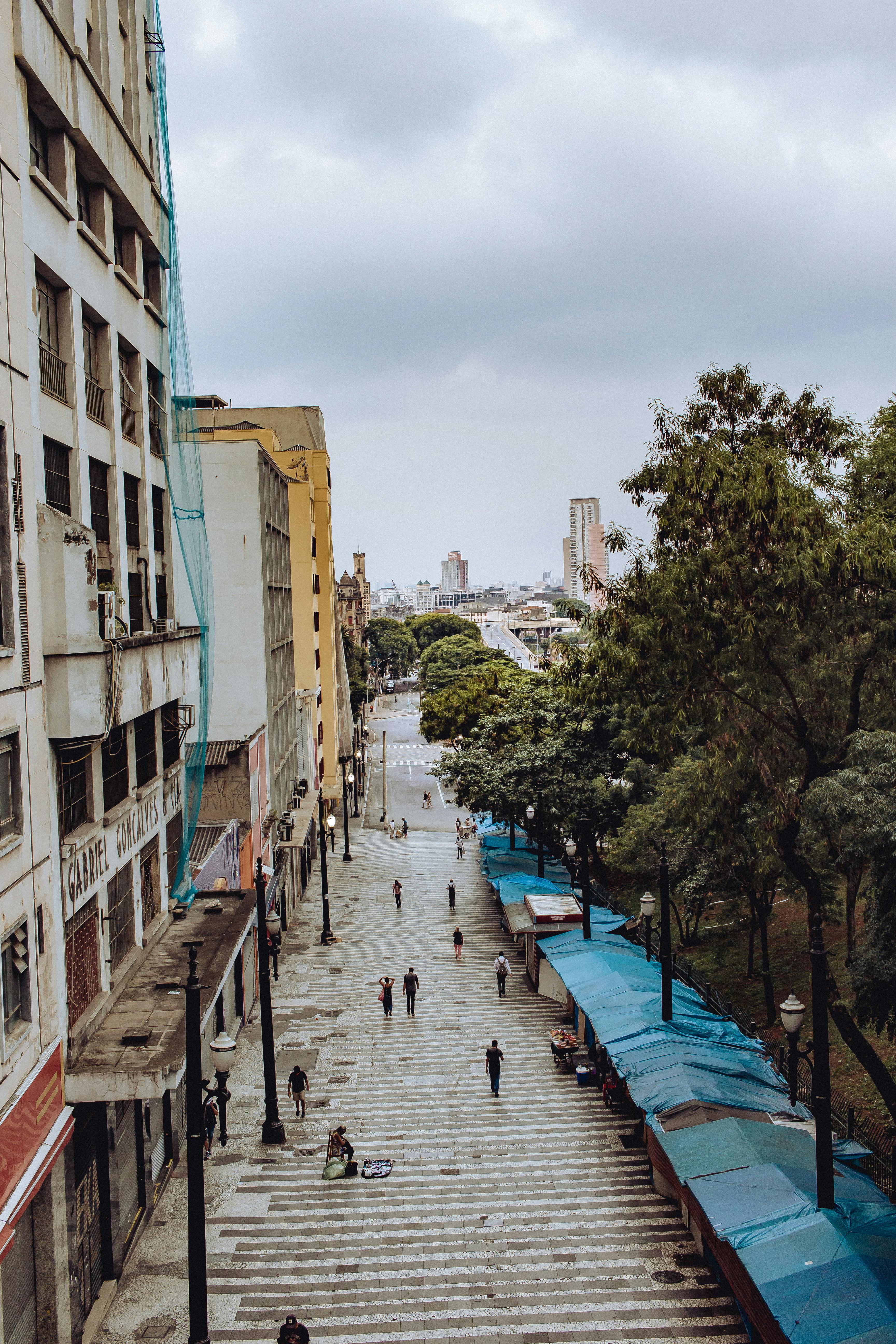 从高处俯瞰白天城市街道的景象，周围有人、树木和高层建筑