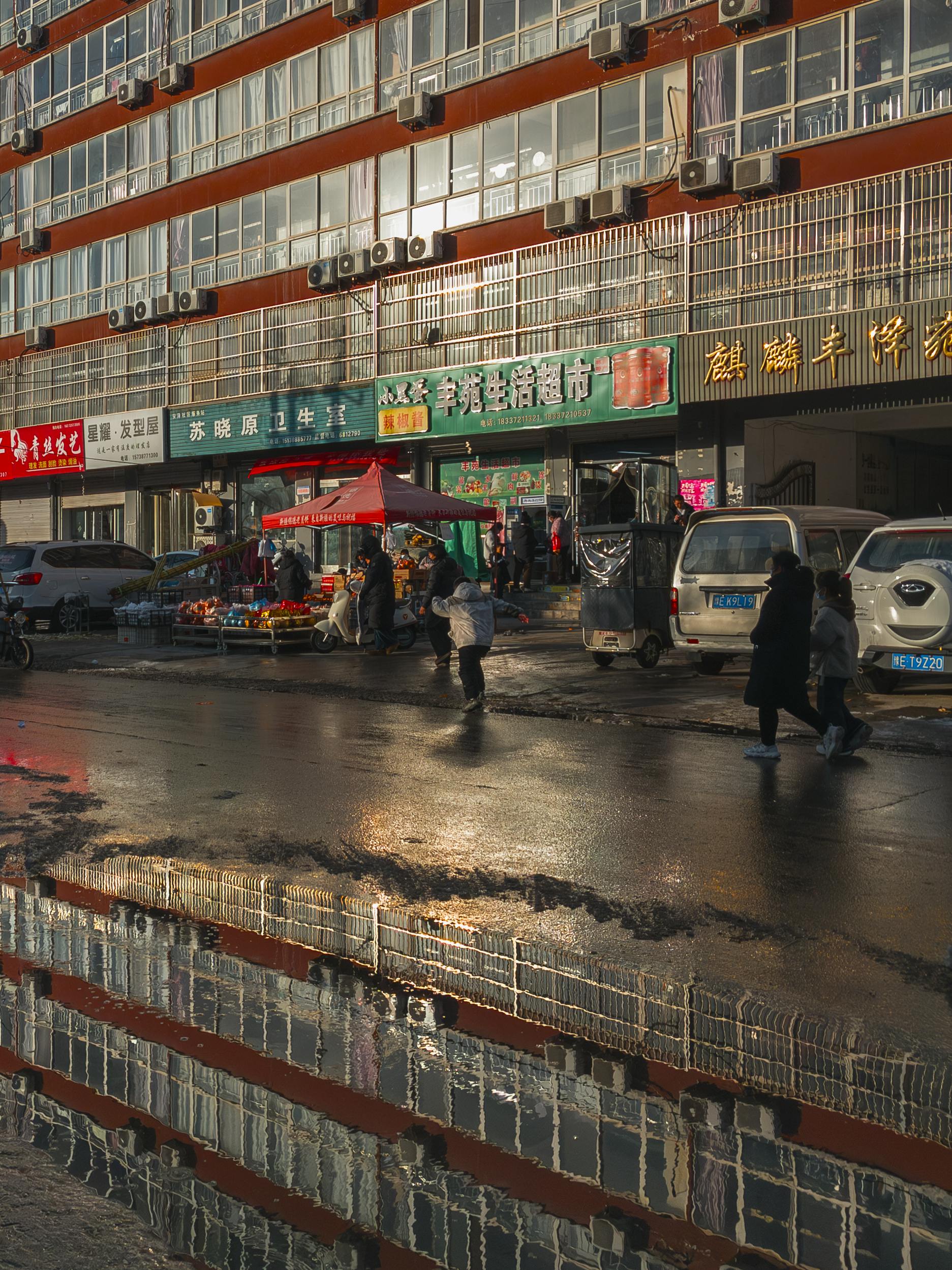 Urban street market with people and reflections in a wet city scene.