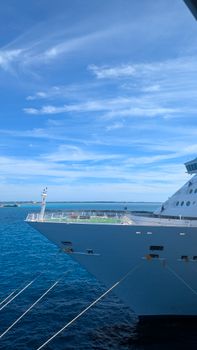 A cruise ship sailing in the ocean under a bright blue sky, displaying a serene seascape.