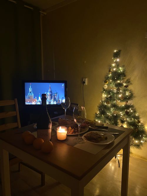 Free Warm and cozy Christmas dinner setup with lights and TV, creating a festive mood. Stock Photo