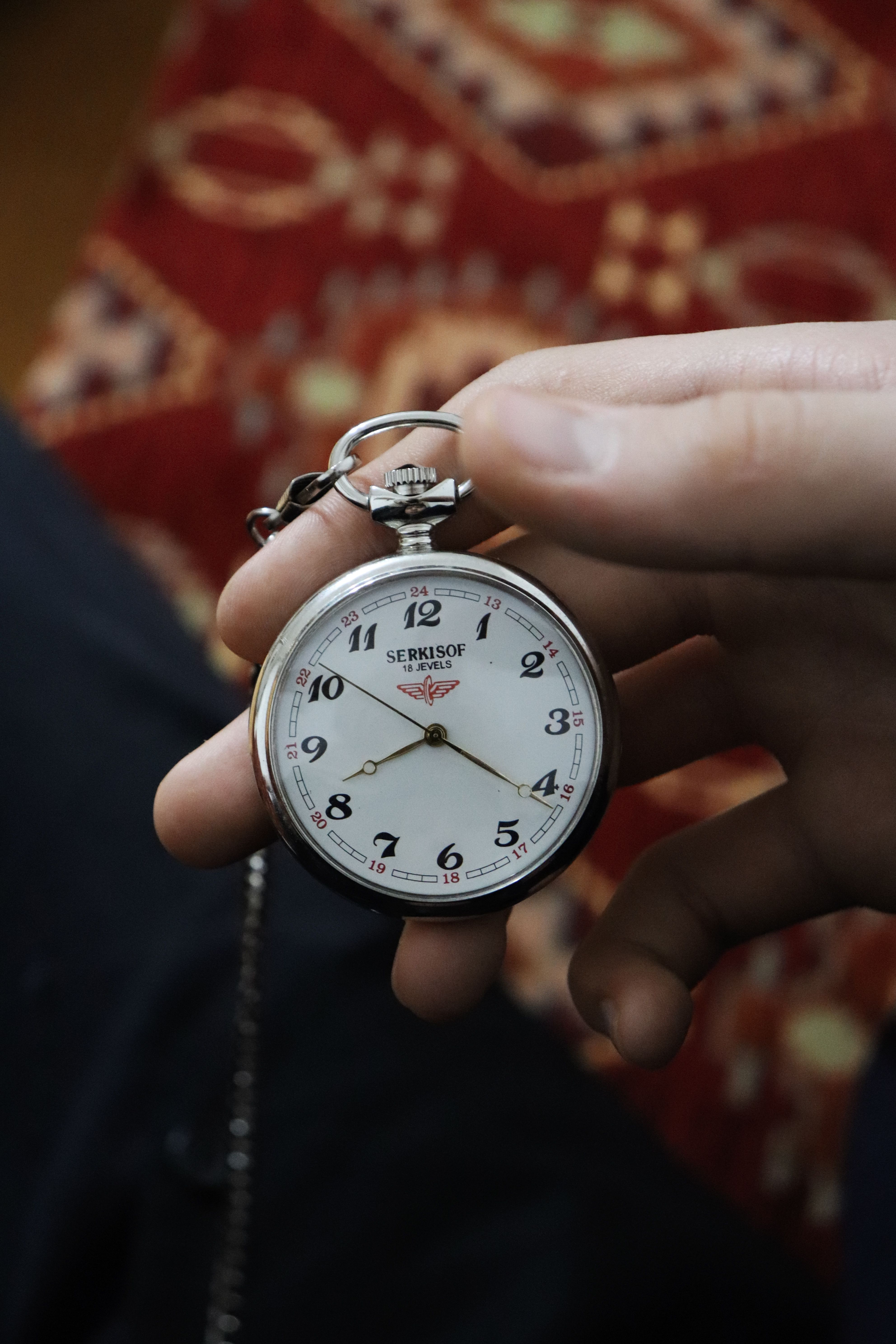 Close-up of a classic pocket watch being held, showcasing its intricate design.
