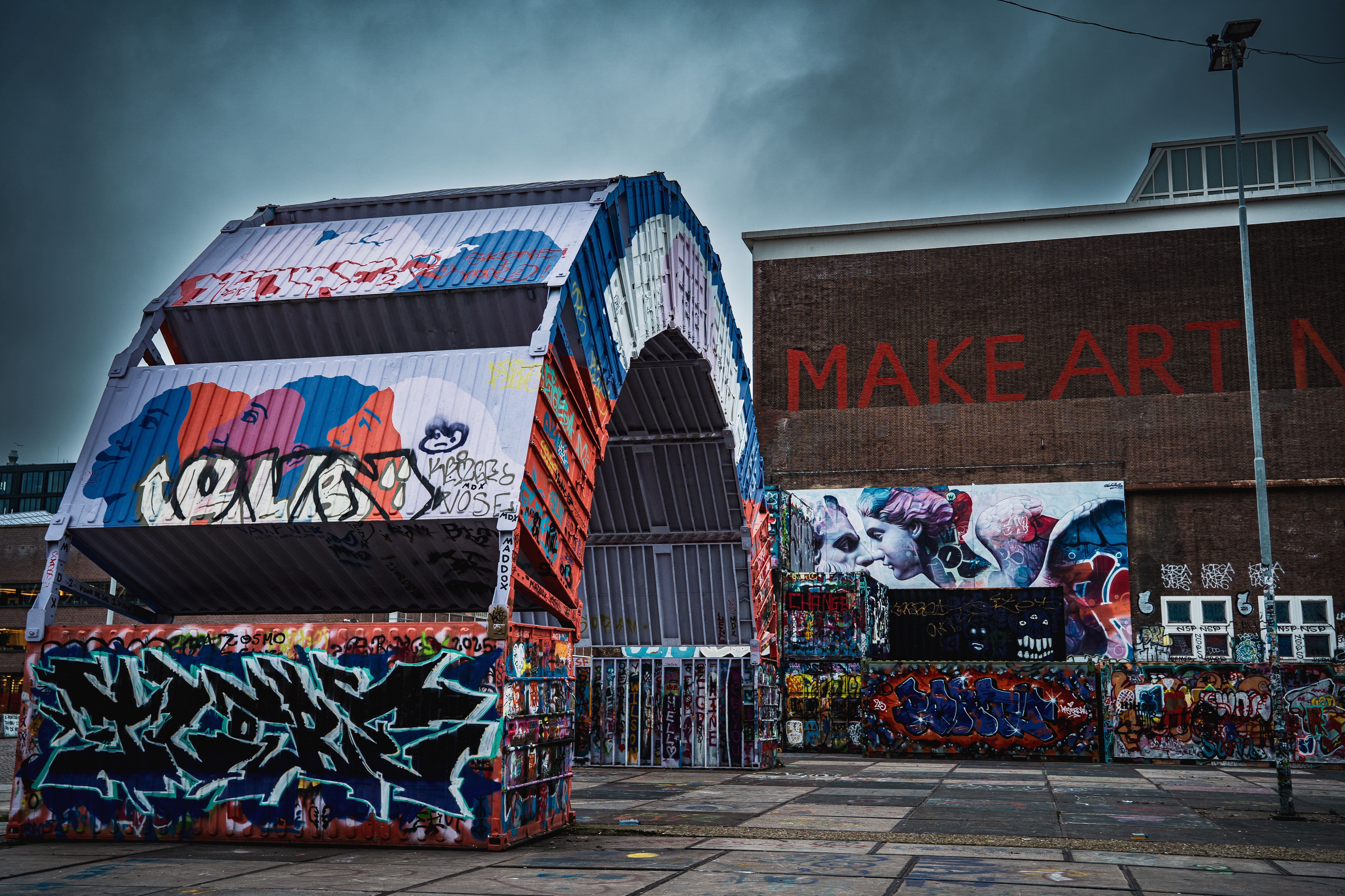 Colorful street art and graffiti adorn a warehouse exterior, creating a striking urban scene.