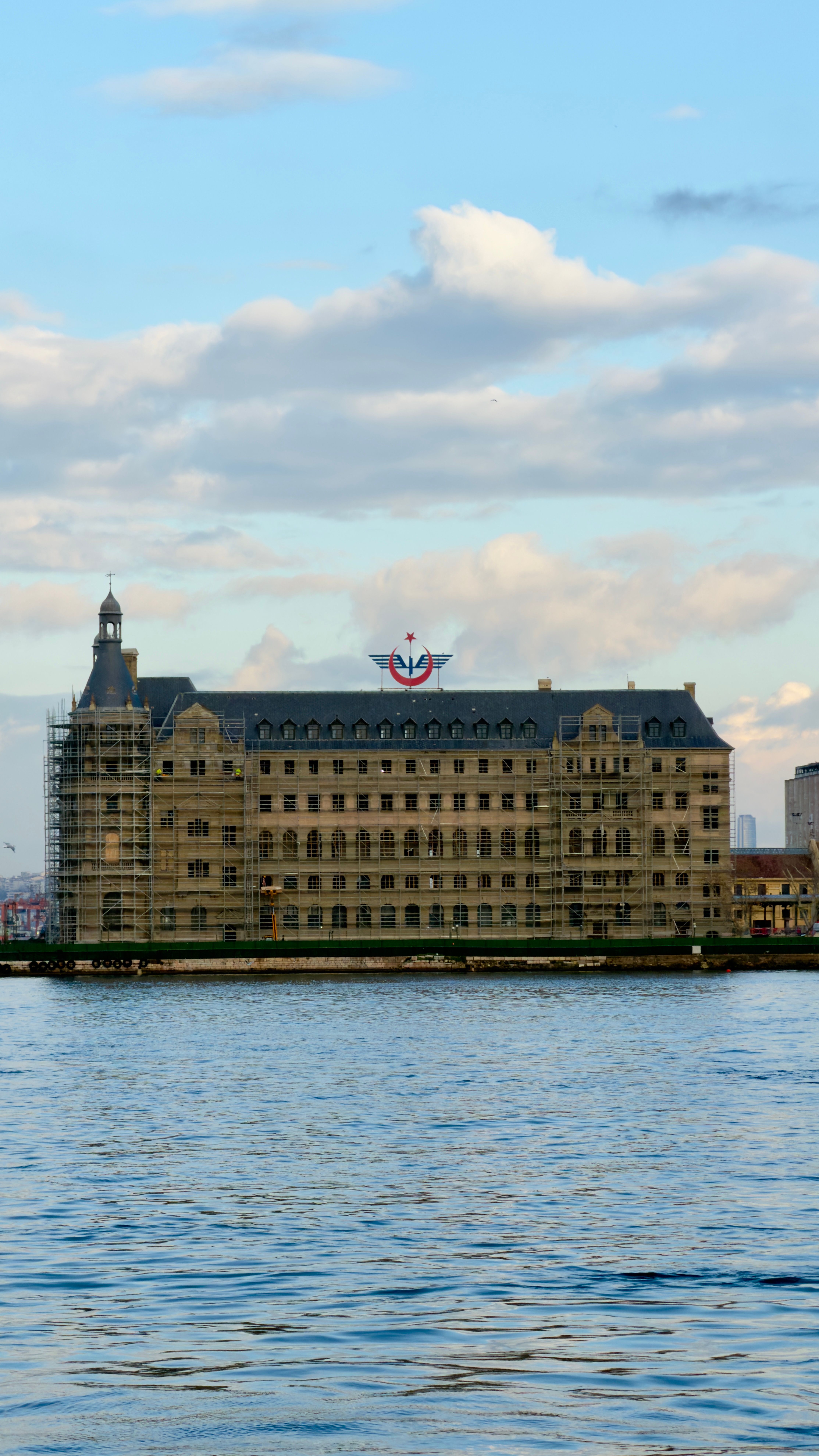 A scenic view of a historic waterfront building in Istanbul with a blue sky backdrop.