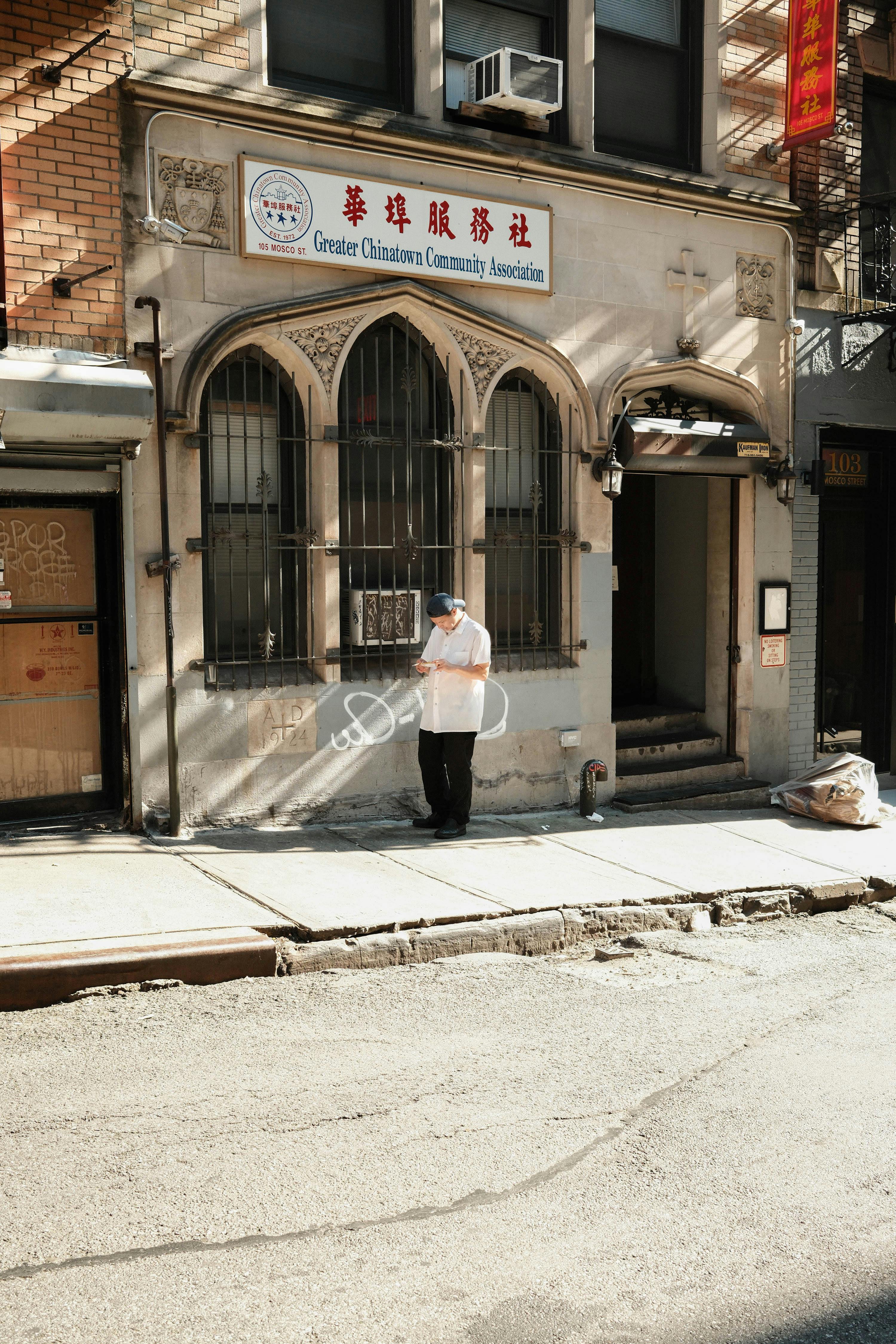 A man stands outside a Chinatown community association building in New York, where local ties can become part of broader influence cases.