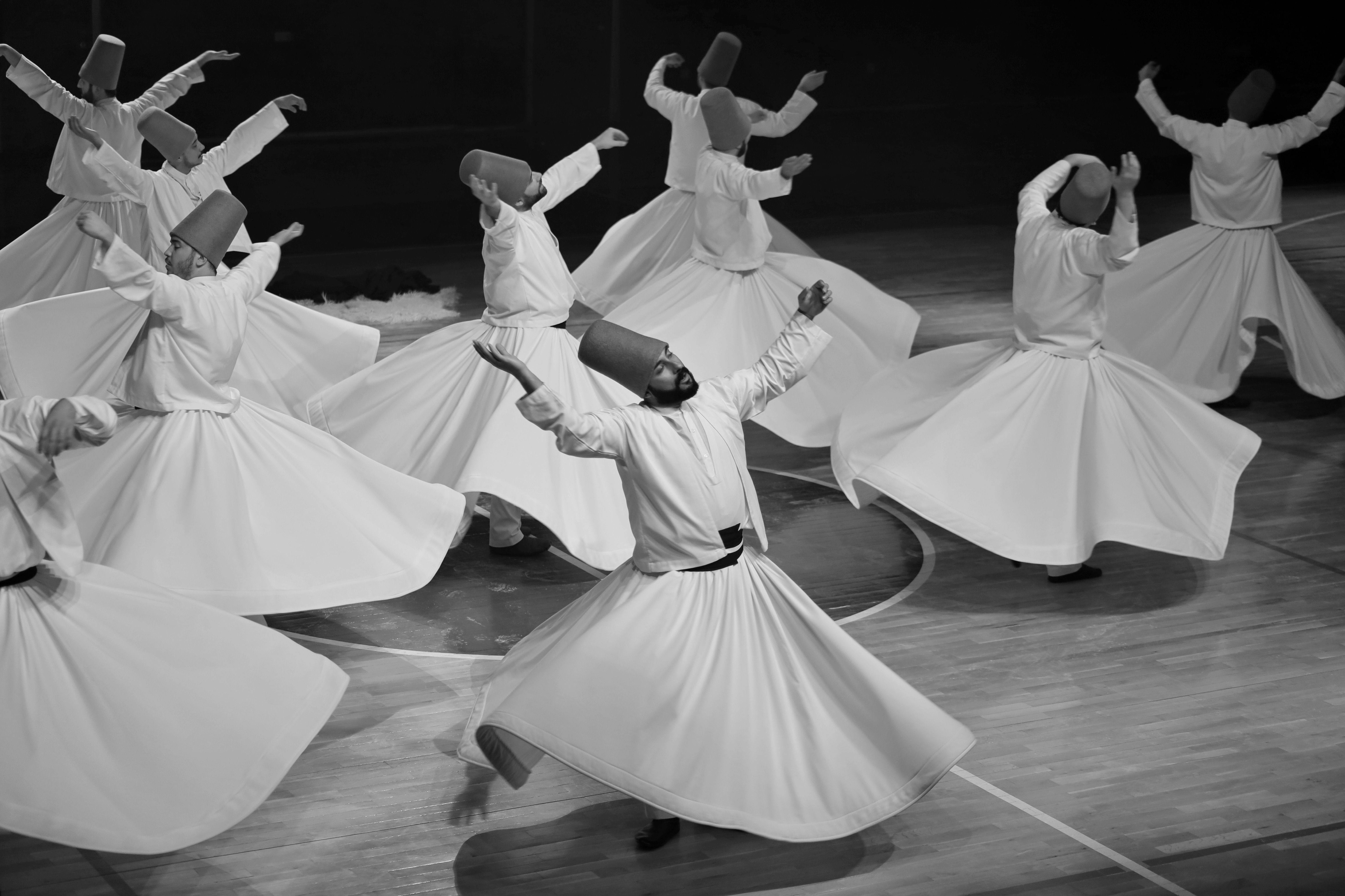 Whirling Dervishes Turkey with white-robed performers spinning in ceremonial Sema ritual under golden light in historic hall