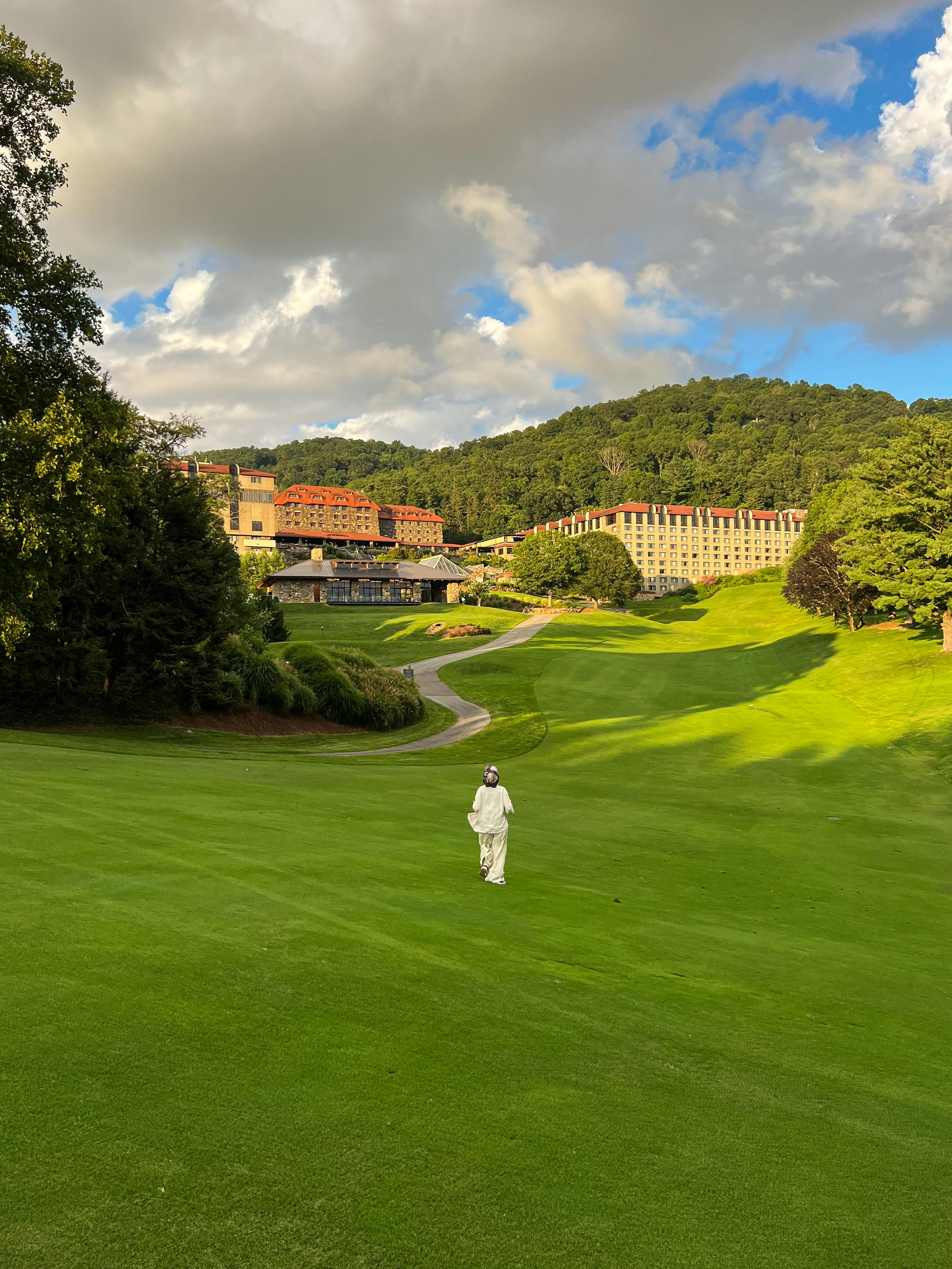 Beautiful view of a golfer on the green at Grove Park Inn, North Carolina, surrounded by lush scenery.