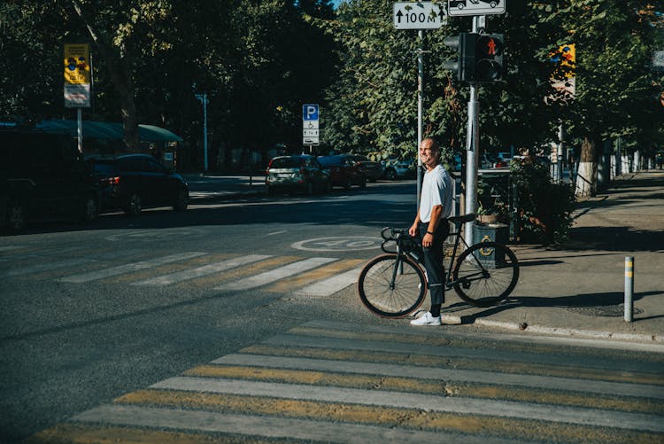 Man Holding Bike In Front Of Pedestrian Lane