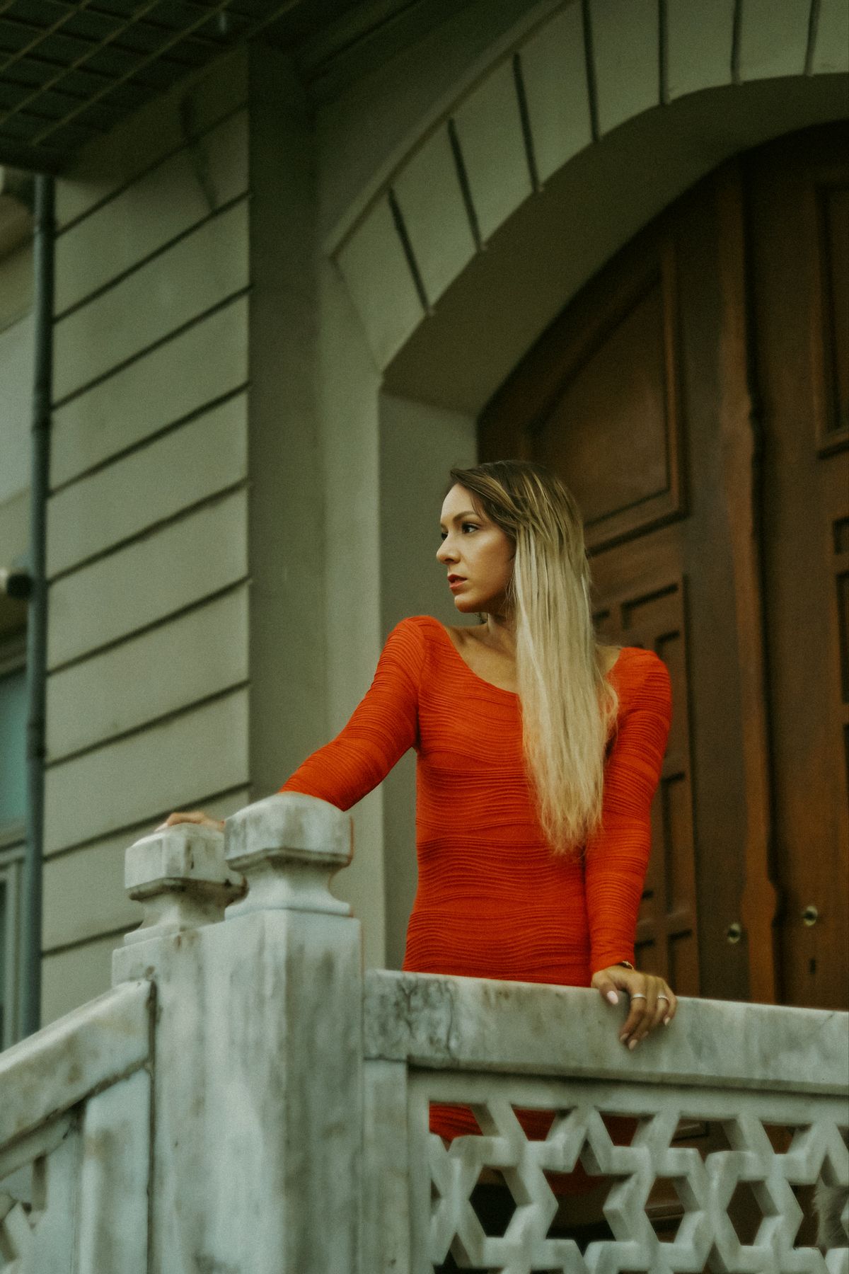 Scarlet Red Outfits for Women — 7 Bold Red Looks for Fall and Winter Woman in a vibrant red dress standing by elegant architecture