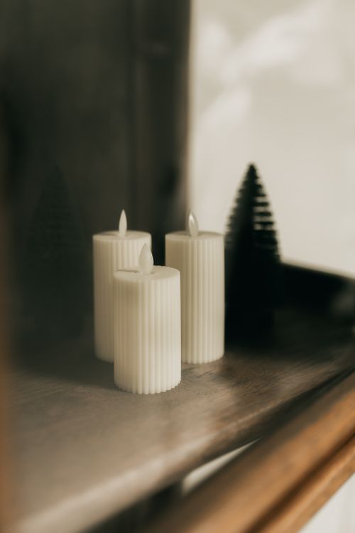 Free Tranquil scene of three elegant white candles on a wooden surface with soft lighting. Stock Photo