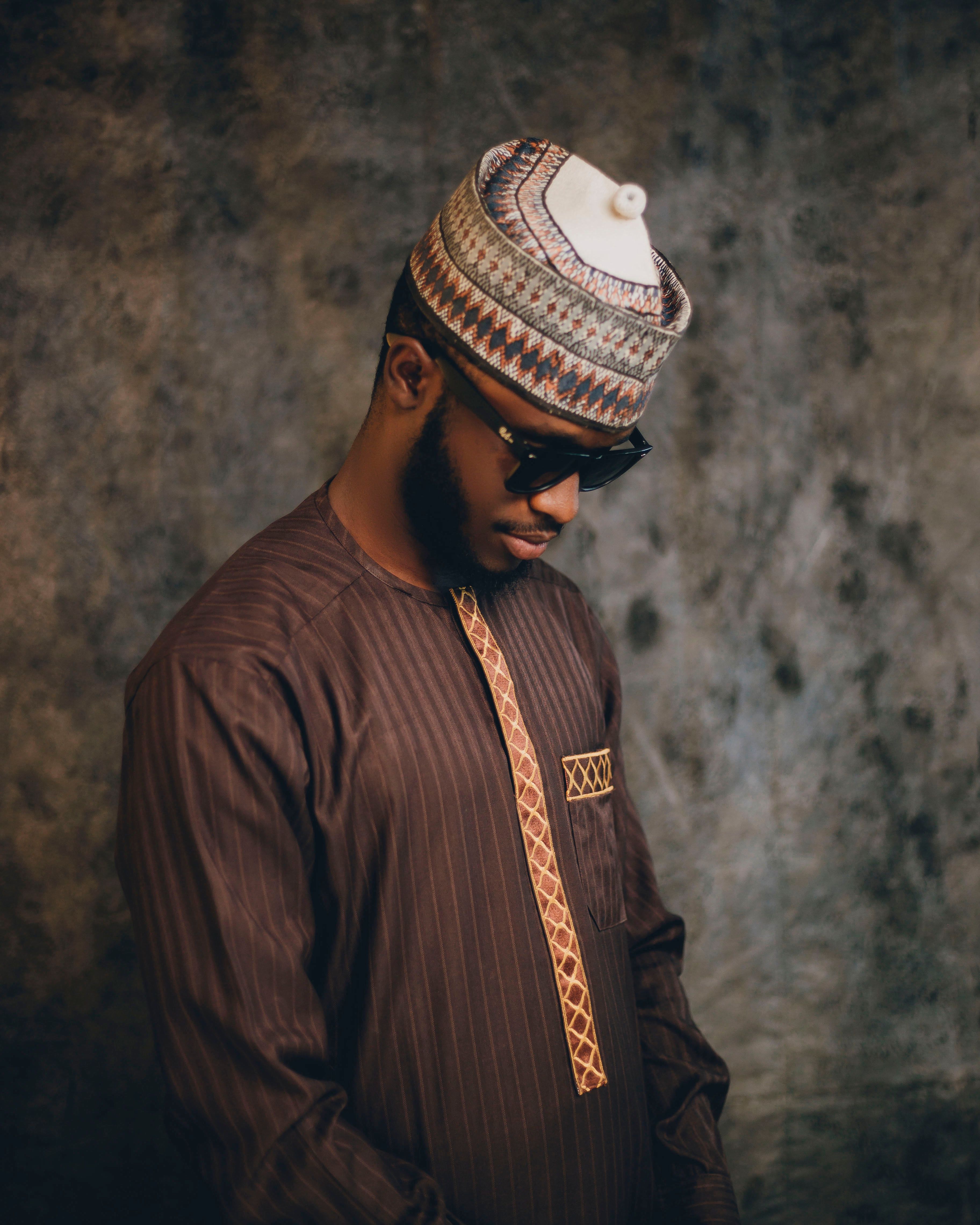 Stylish portrait of a man in traditional Nigerian dress with a textured background, exuding cultural richness.