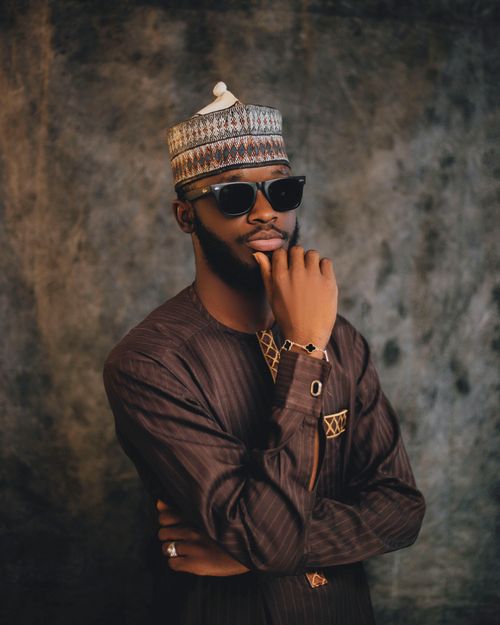 Free Confident man in traditional attire and sunglasses posing against a textured backdrop. Stock Photo