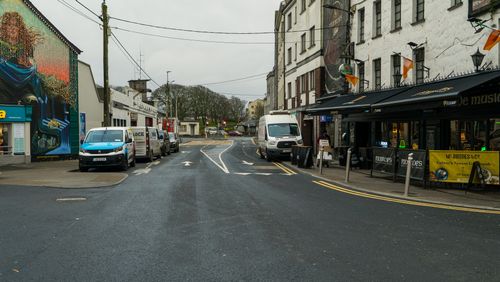 Free A city street in Galway featuring vibrant mural, parked vehicles, and Irish pub. Stock Photo