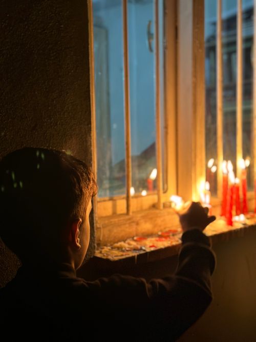 Free A young child lights candles by a window, creating a warm and inviting atmosphere. Stock Photo