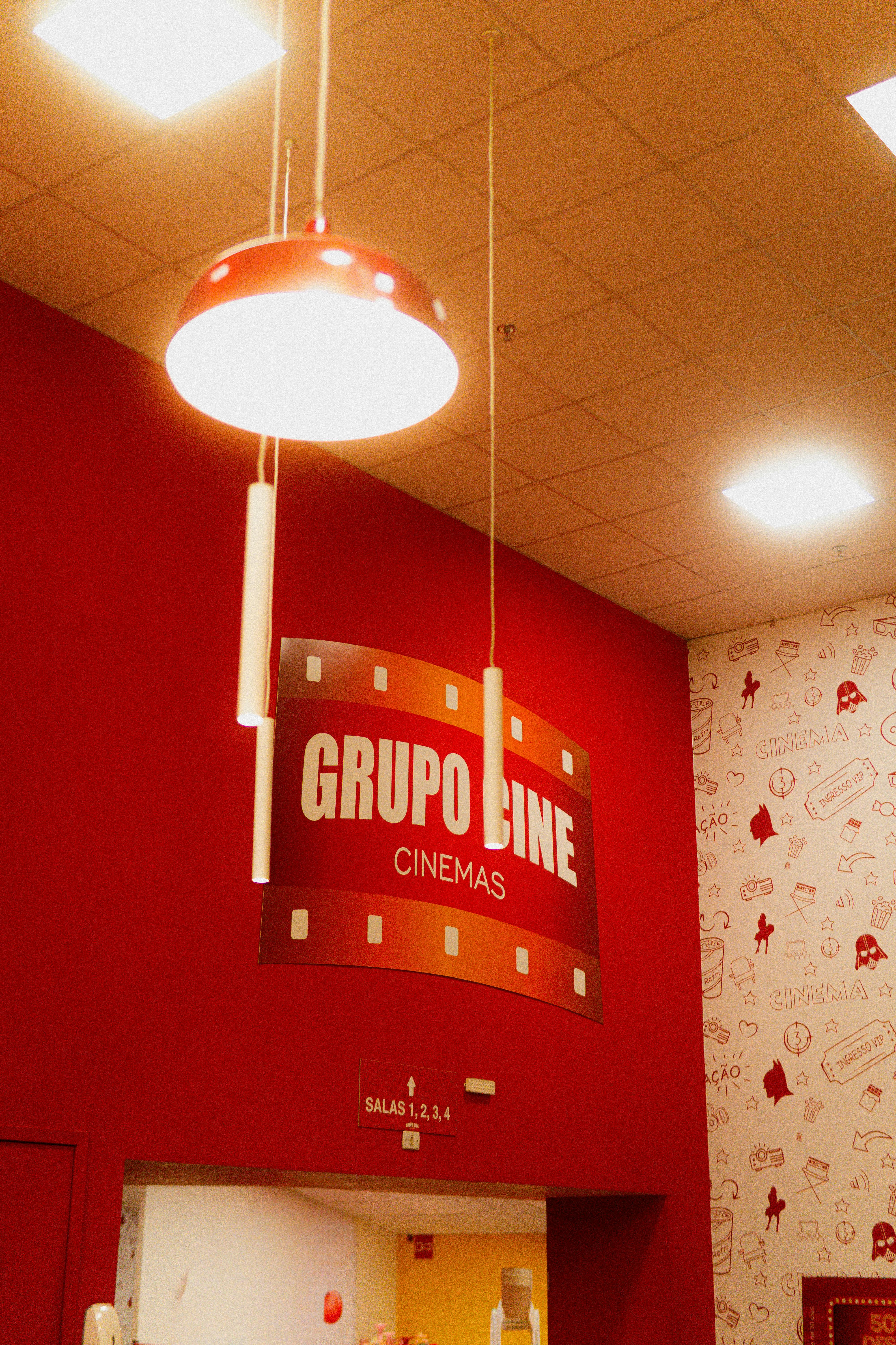 Free Red-themed cinema entrance with a vibrant Grupo Line sign and overhead lighting. Stock Photo