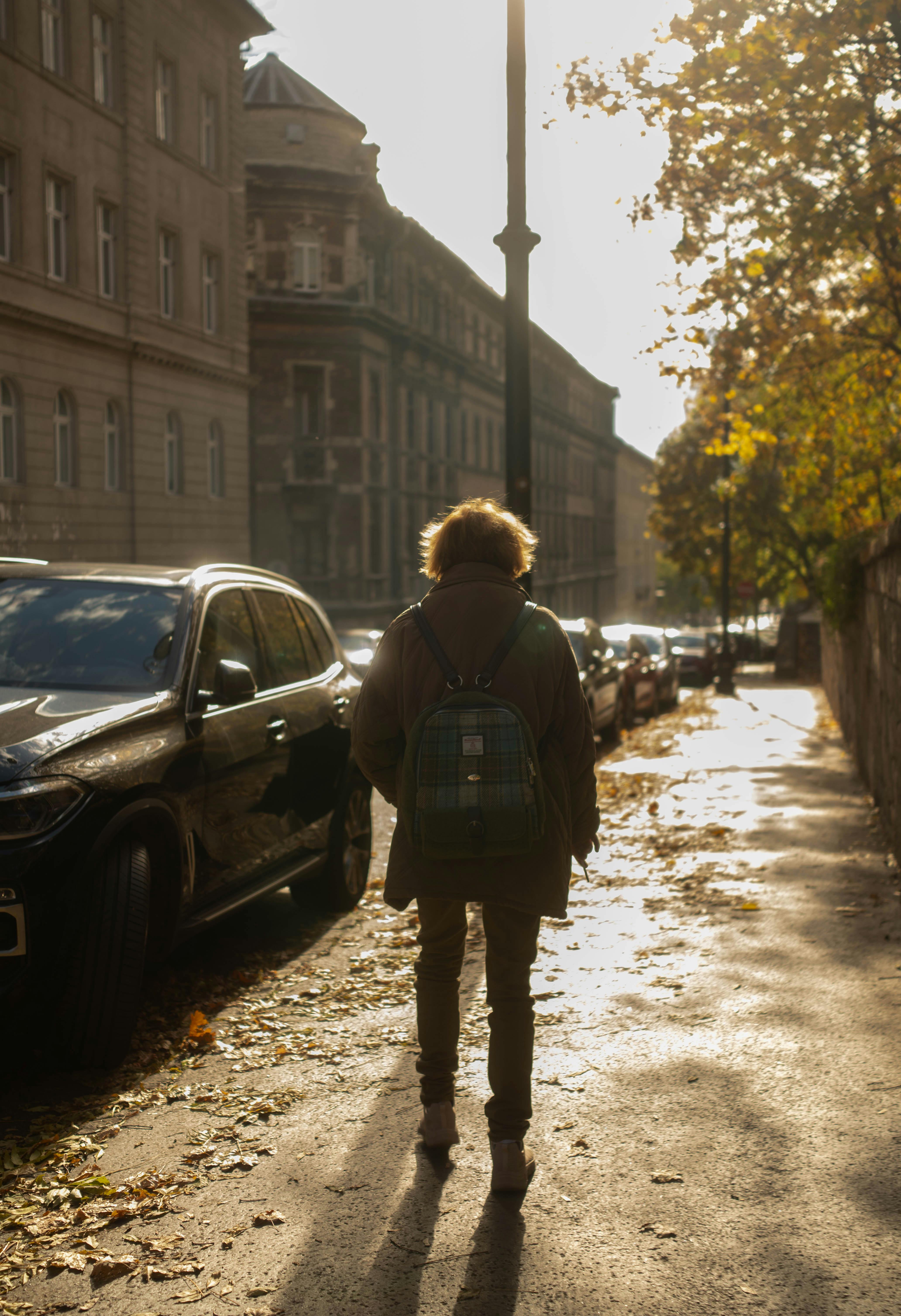Back view of a person walking on a sunny autumn street in Budapest, Hungary.