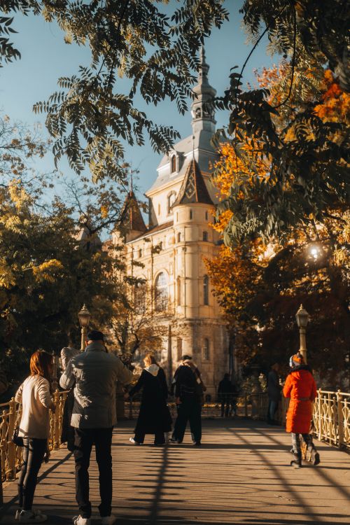 Free People walking on a bridge surrounded by autumn foliage, near iconic architecture in Budapest. Stock Photo