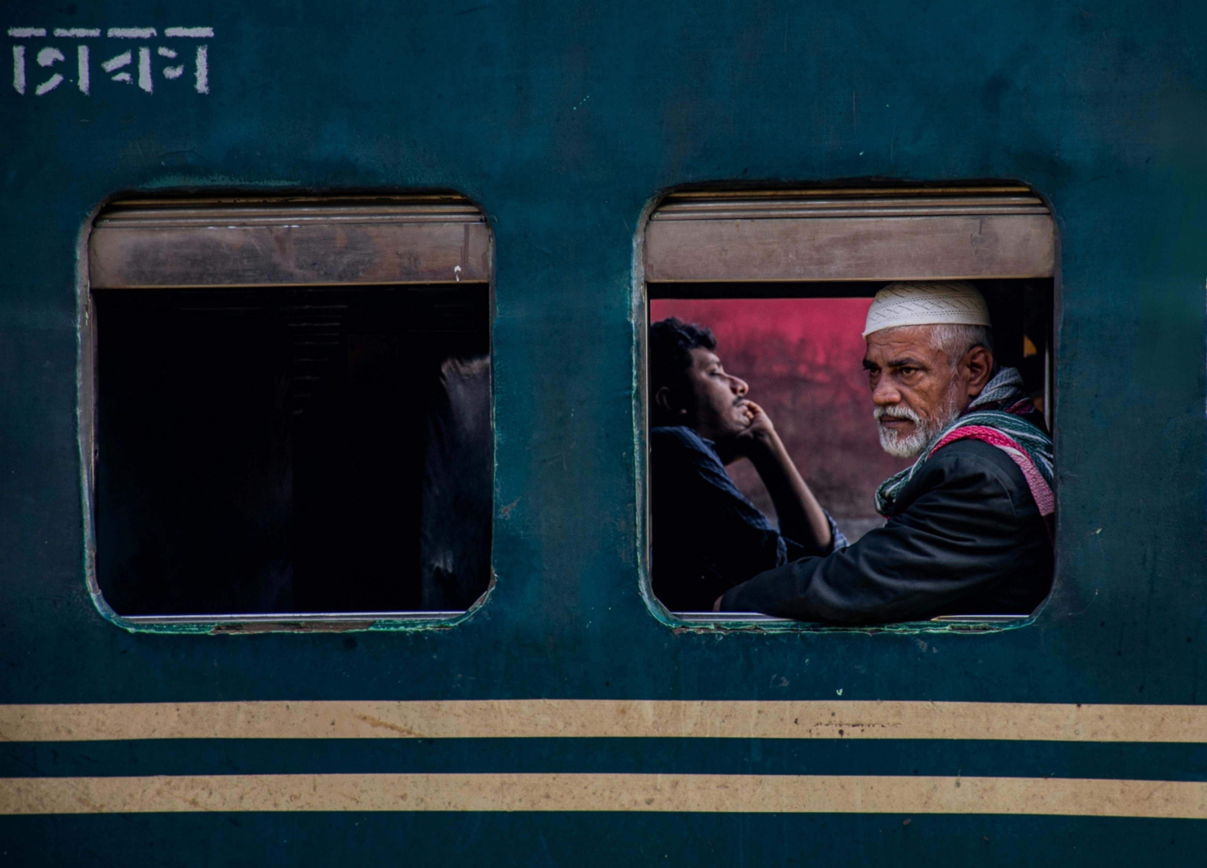 Passengers looking out a train window in Bangladesh, capturing daily life moments.