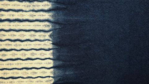 Close-up of indigo-dyed fabric featuring a wave pattern transitioning from light to dark blue.
