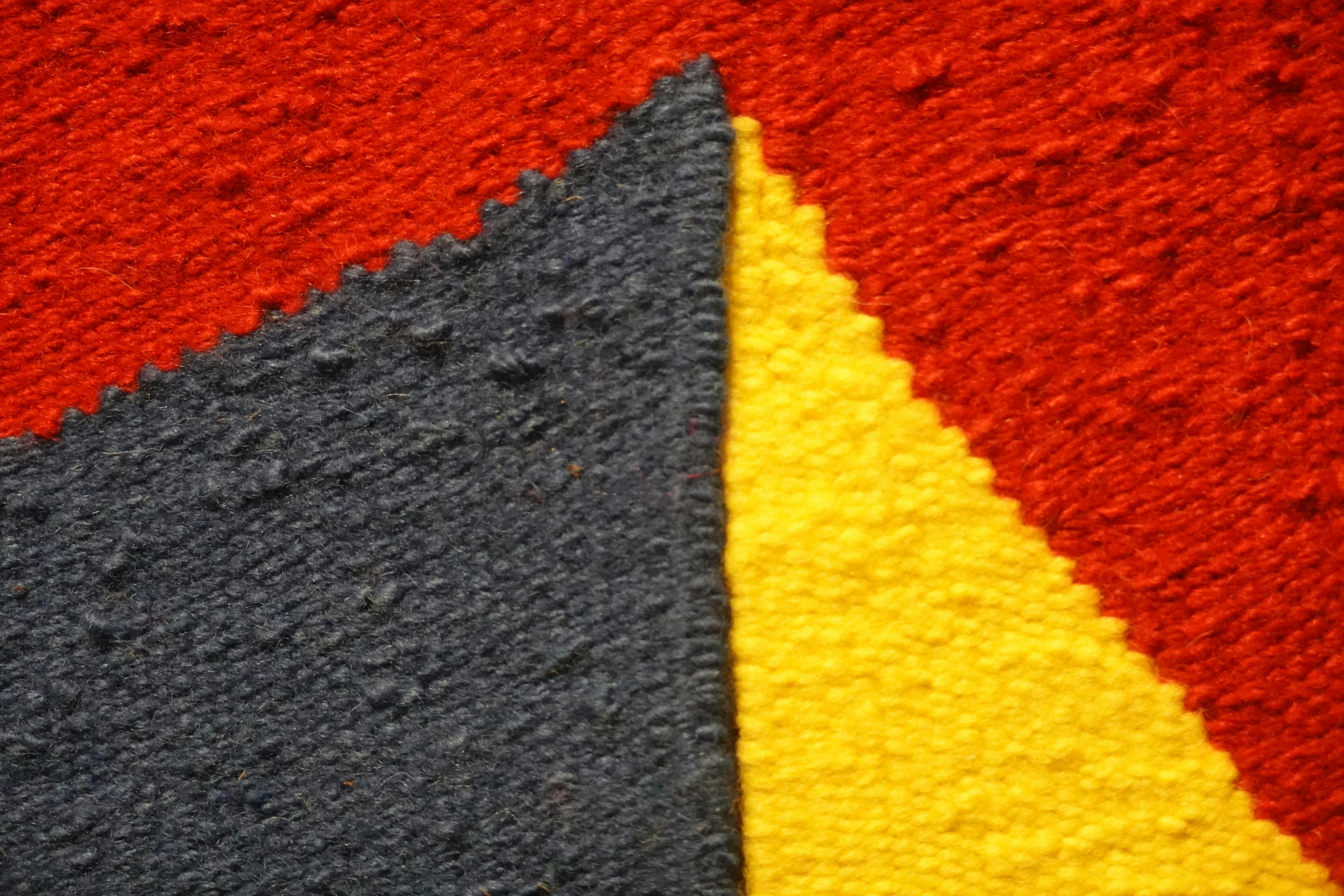 Free Close-up of a colorful textile pattern featuring red, yellow, and blue geometric shapes. Stock Photo