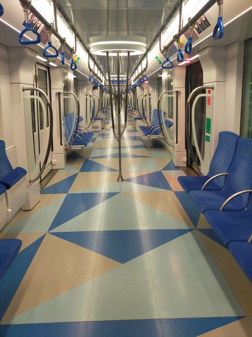 Free A clean, empty subway train interior with blue seats and geometric floor pattern. Stock Photo