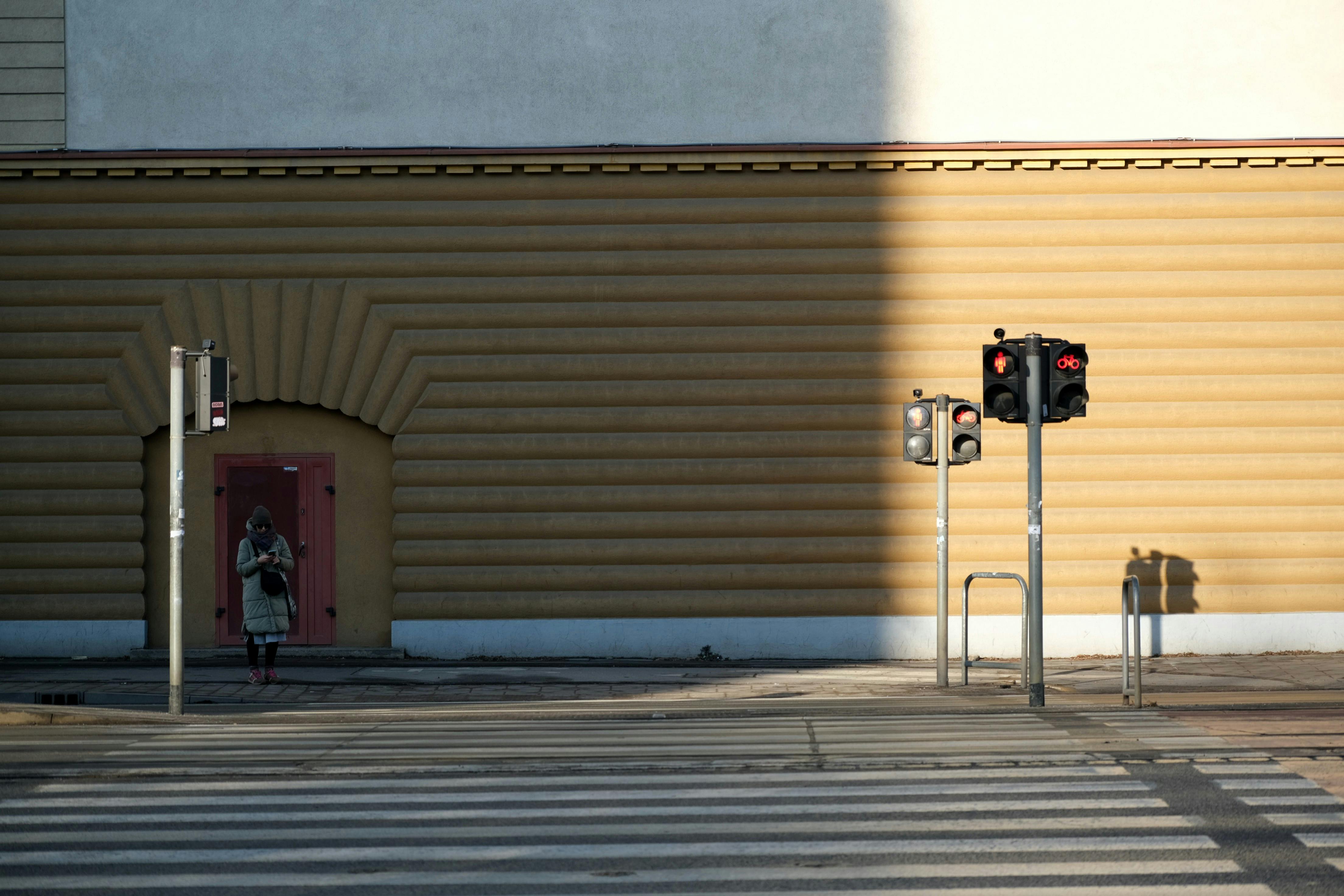 Gratis Urban gatemiljø som fanger en enslig fotgjenger med trafikklys som kaster lange skygger. Arkivbilde