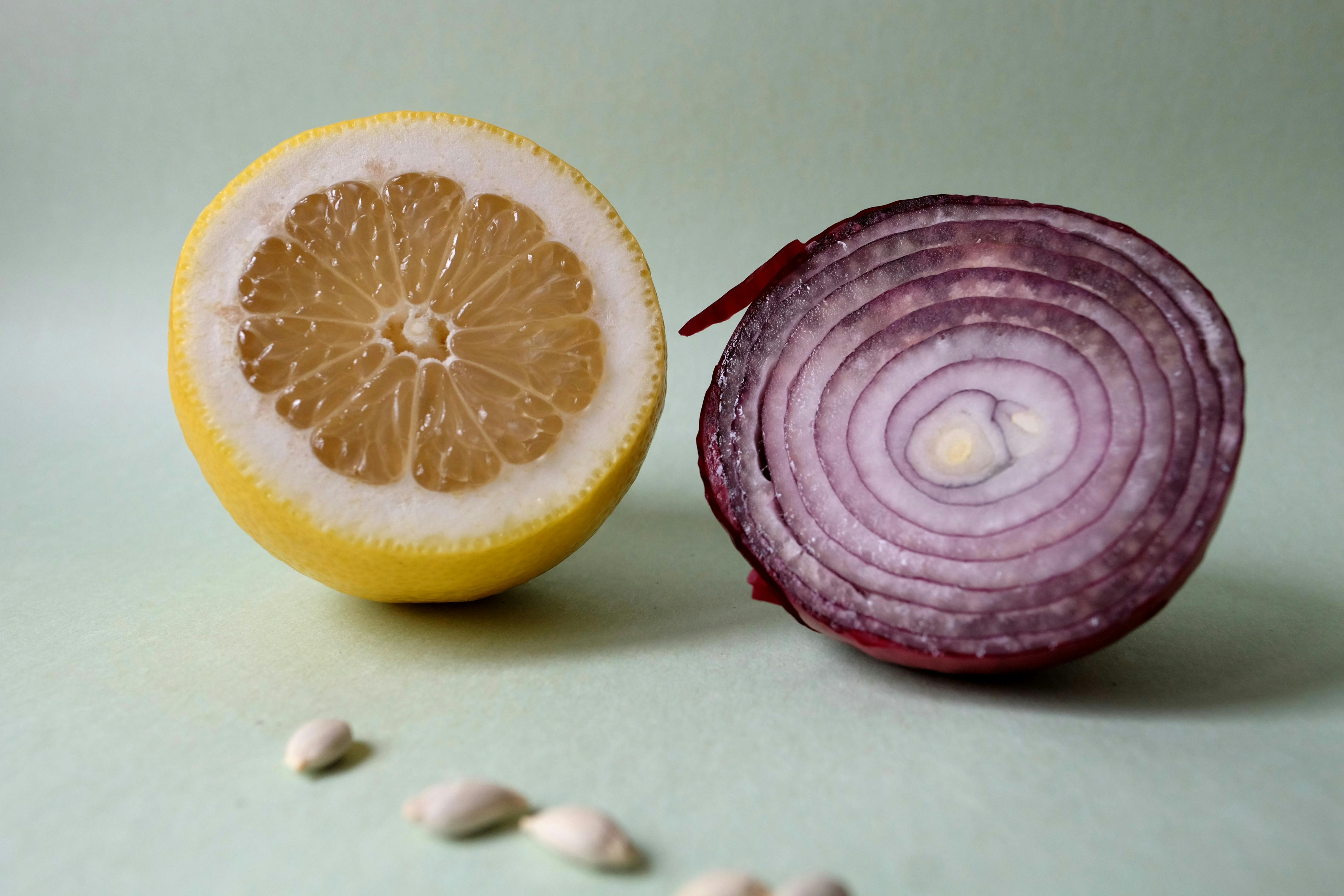 Artistic composition of sliced lemon and red onion on a pastel backdrop, highlighting their textures.