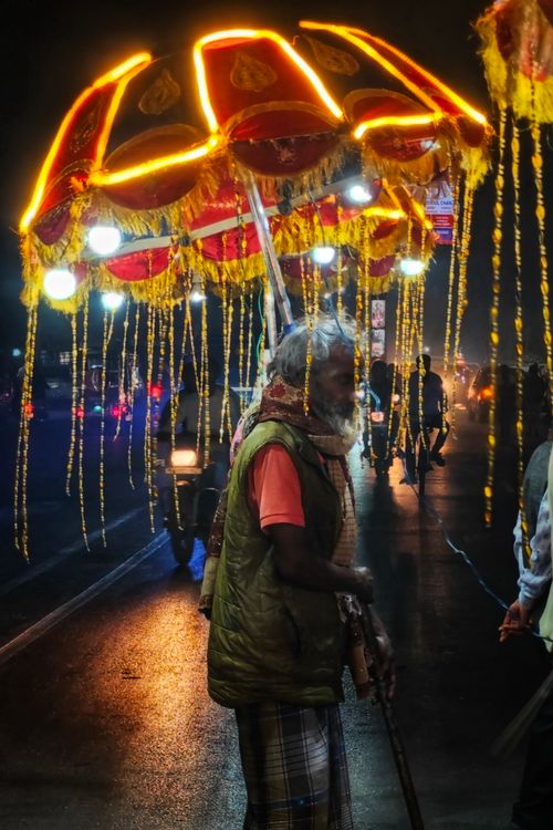 Free A traditional illuminated umbrella carried by a street performer in Varanasi, India, showcasing cultural richness. Stock Photo