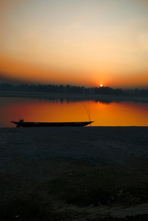 Free Tranquil sunrise over a quiet lake with a silhouette of a boat. Perfect for peaceful and relaxing themes. Stock Photo