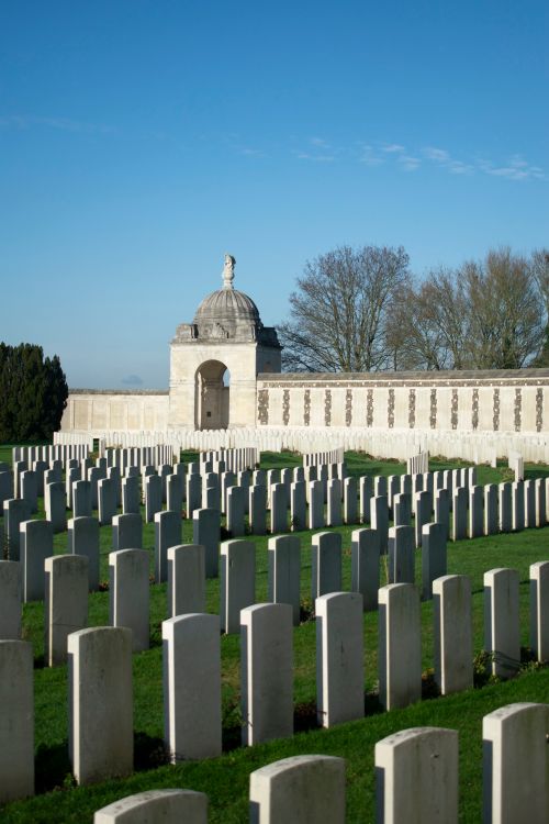 Free Rows of gravestones at a serene war cemetery with a memorial archway. Stock Photo