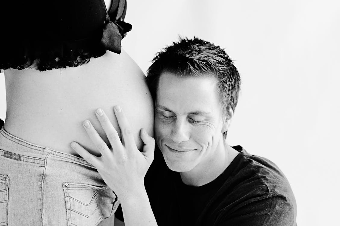 Man Wearing Black Listening on Pregnant Woman's Stomach