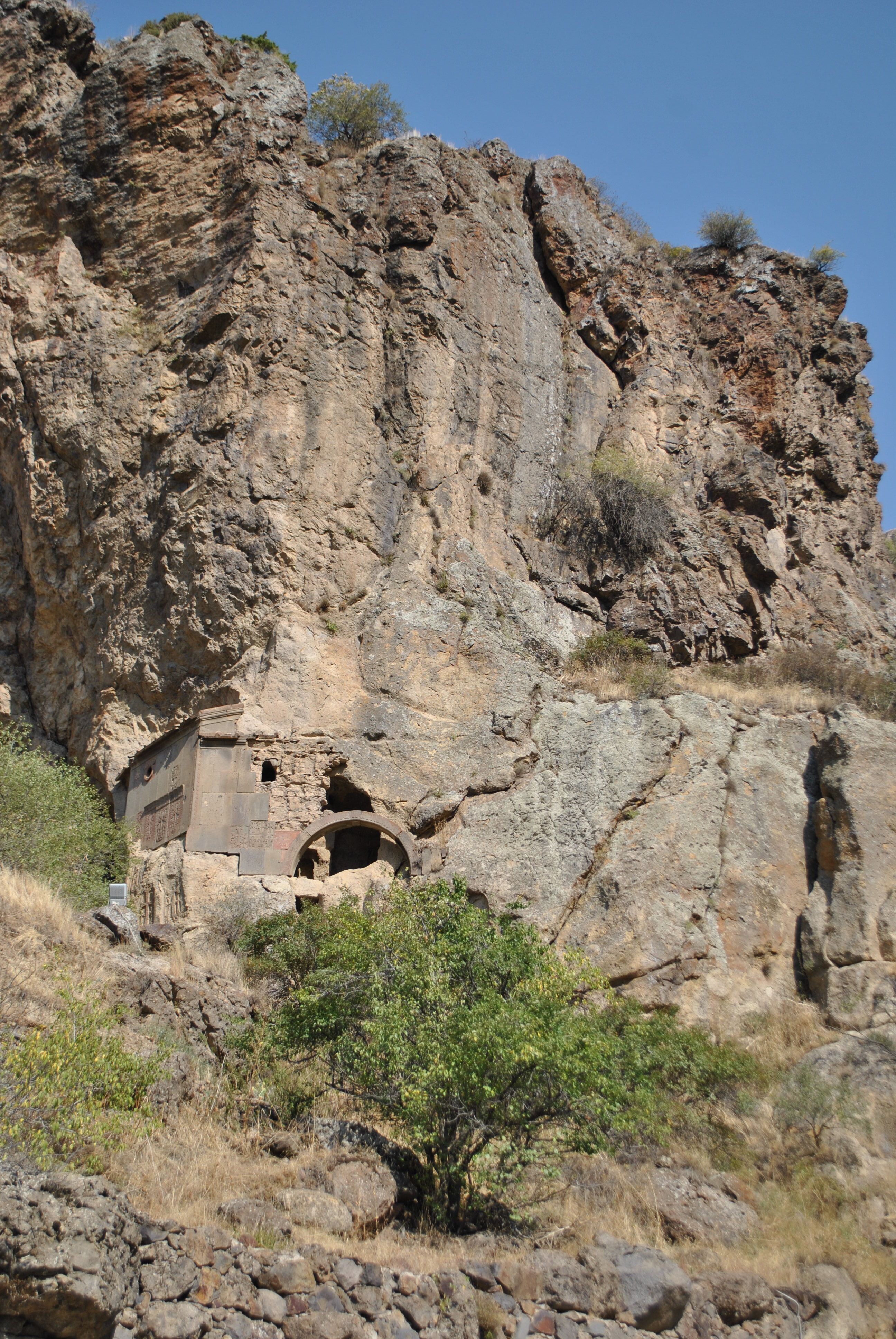 Explore an ancient stone building nestled into rugged cliff formations.