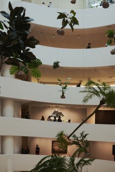 Modern interior of Guggenheim Museum, New York, with visitors and hanging plants.