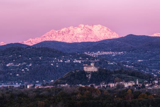 Majestic snowy Alps over Italian townscapes during sunset.