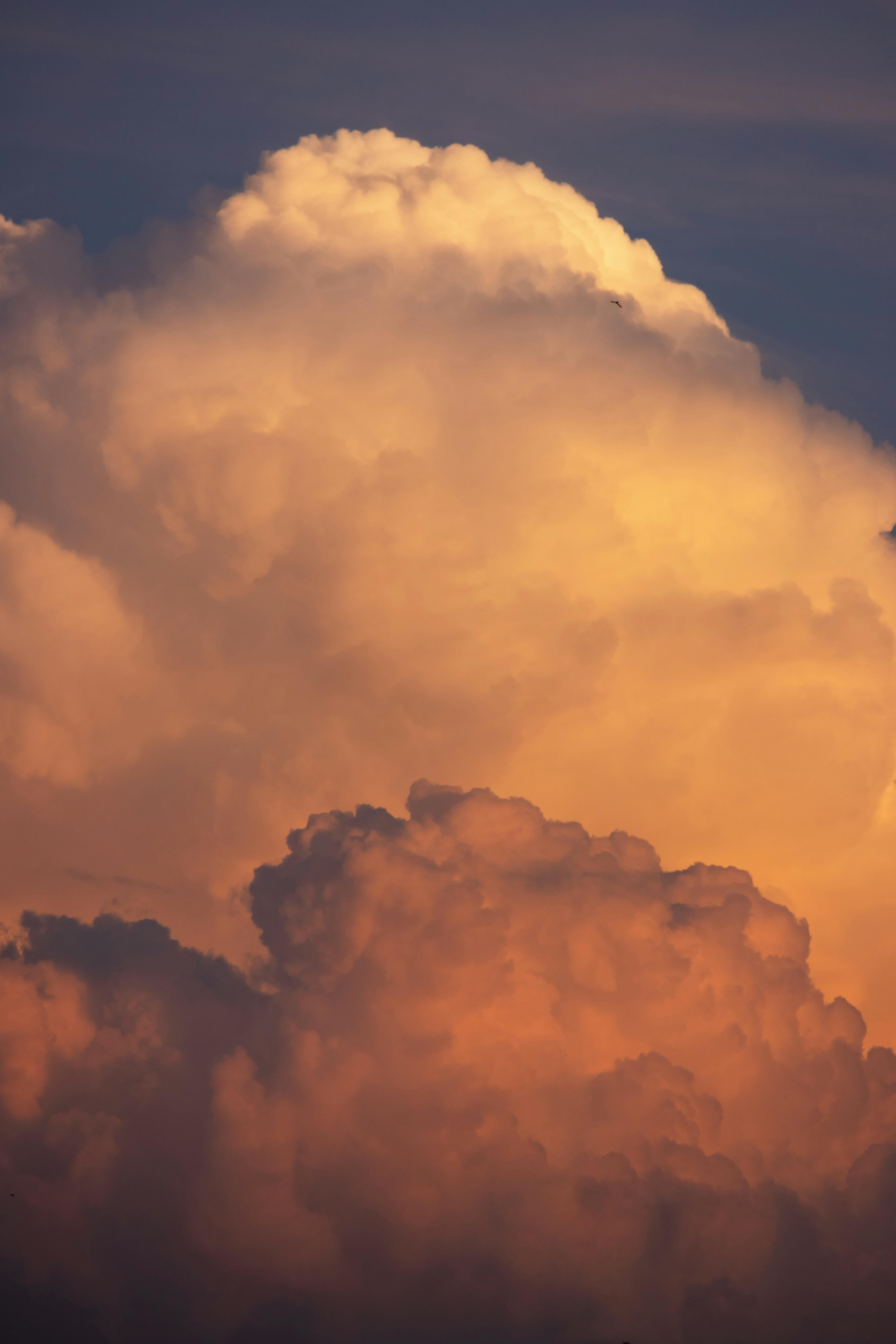 A stunning view of dramatic cumulus and cumulonimbus clouds during sunset with warm hues.