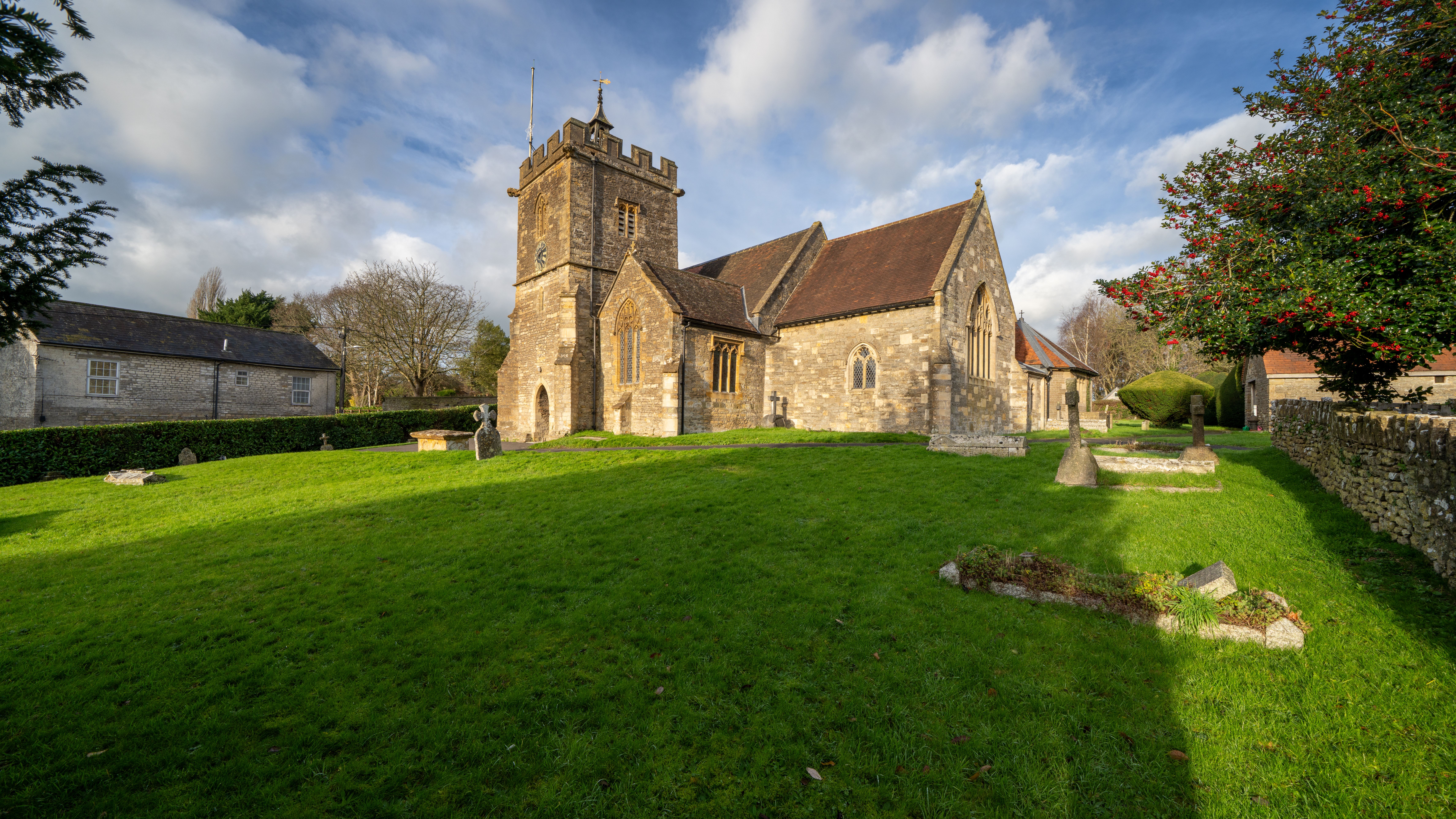 Charming historic church in Templecombe, England with surrounding greenery under a bright sky.