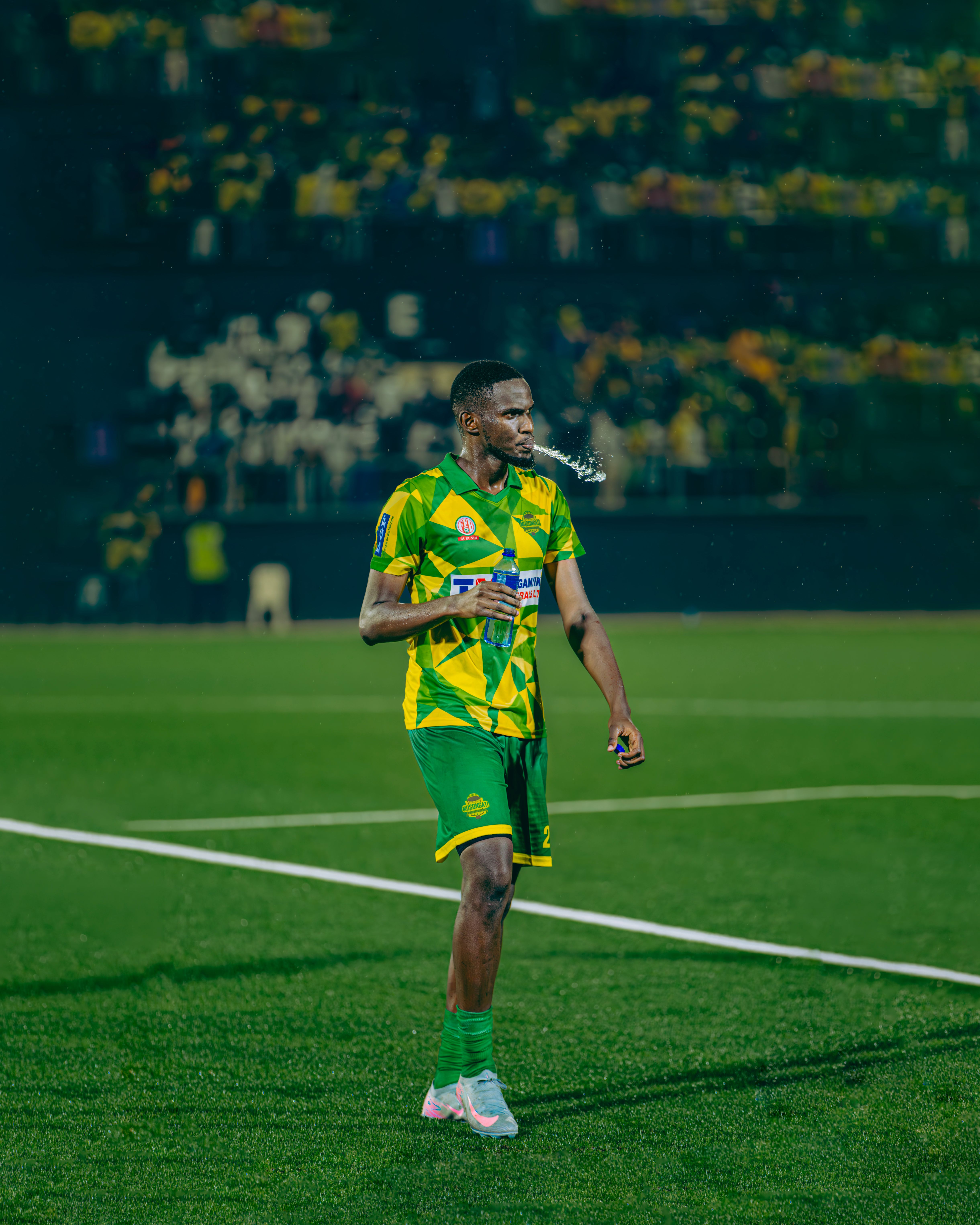 A soccer player on the field at night during a match in Burundi.