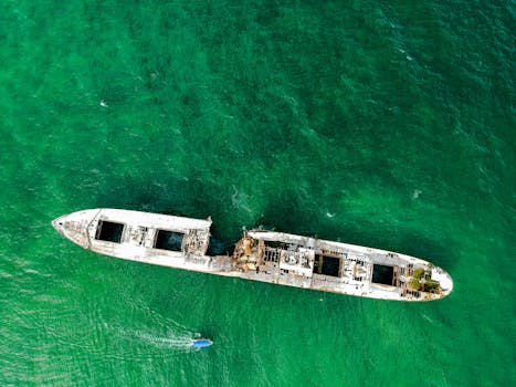 Aerial view of a sunken ship surrounded by turquoise water, showcasing marine exploration and history.