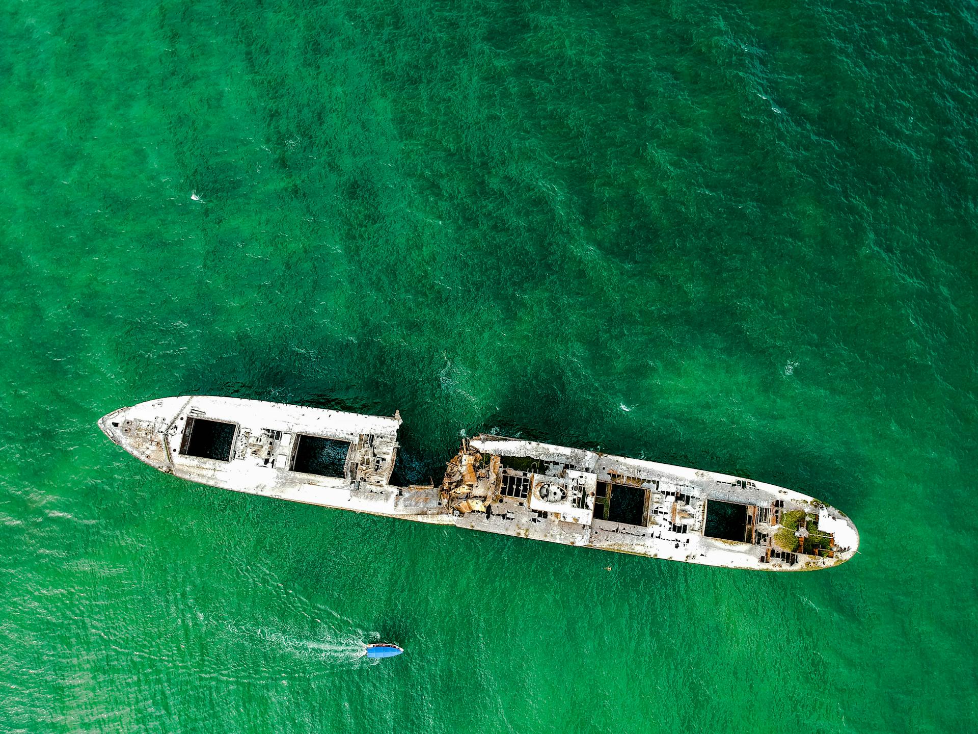 Aerial view of a sunken ship surrounded by turquoise water, showcasing marine exploration and history.