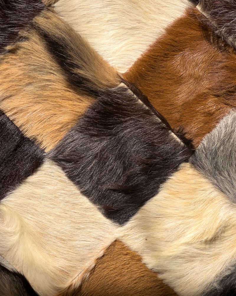 Close-up of handmade cowhide patchwork rug showing diamond-shaped hide pieces in natural tones