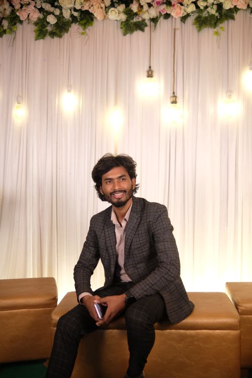 Free Portrait of a man in a suit smiling at a decorated indoor event setting. Stock Photo