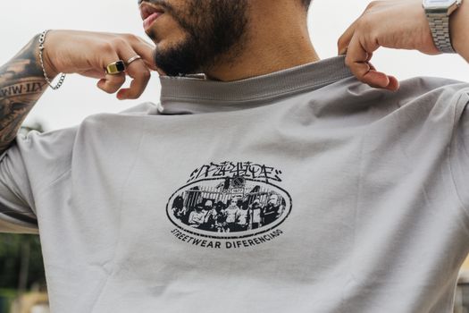 A fashionable man displays a graphic streetwear t-shirt outdoors in São Paulo, Brazil.