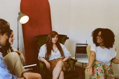 Four adults engaged in a relaxed group discussion in a cozy indoor space.
