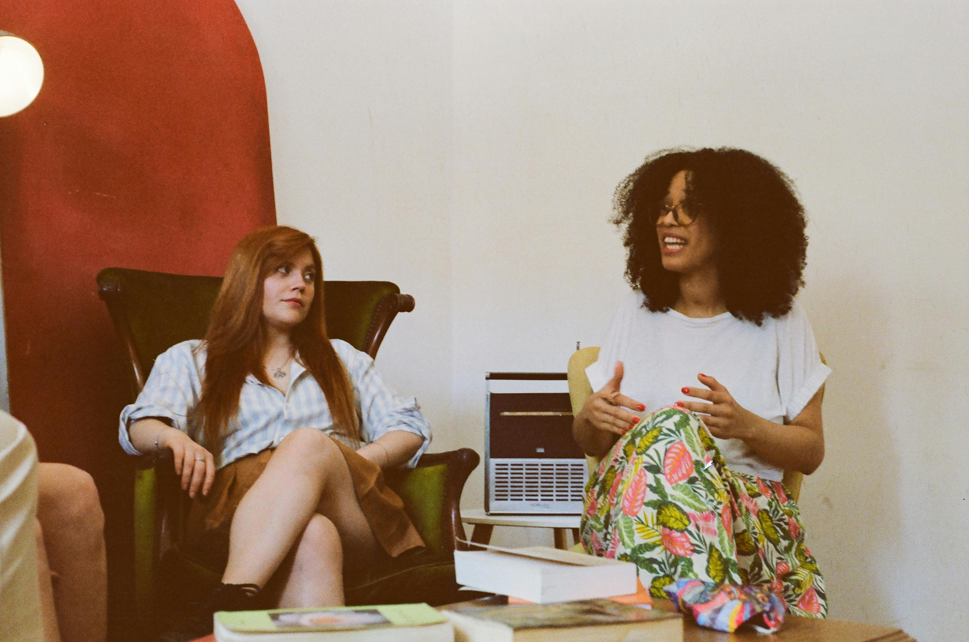 Kostnadsfria Två kvinnor förde en avslappnad diskussion i en mysig inomhusmiljö. Stock foto