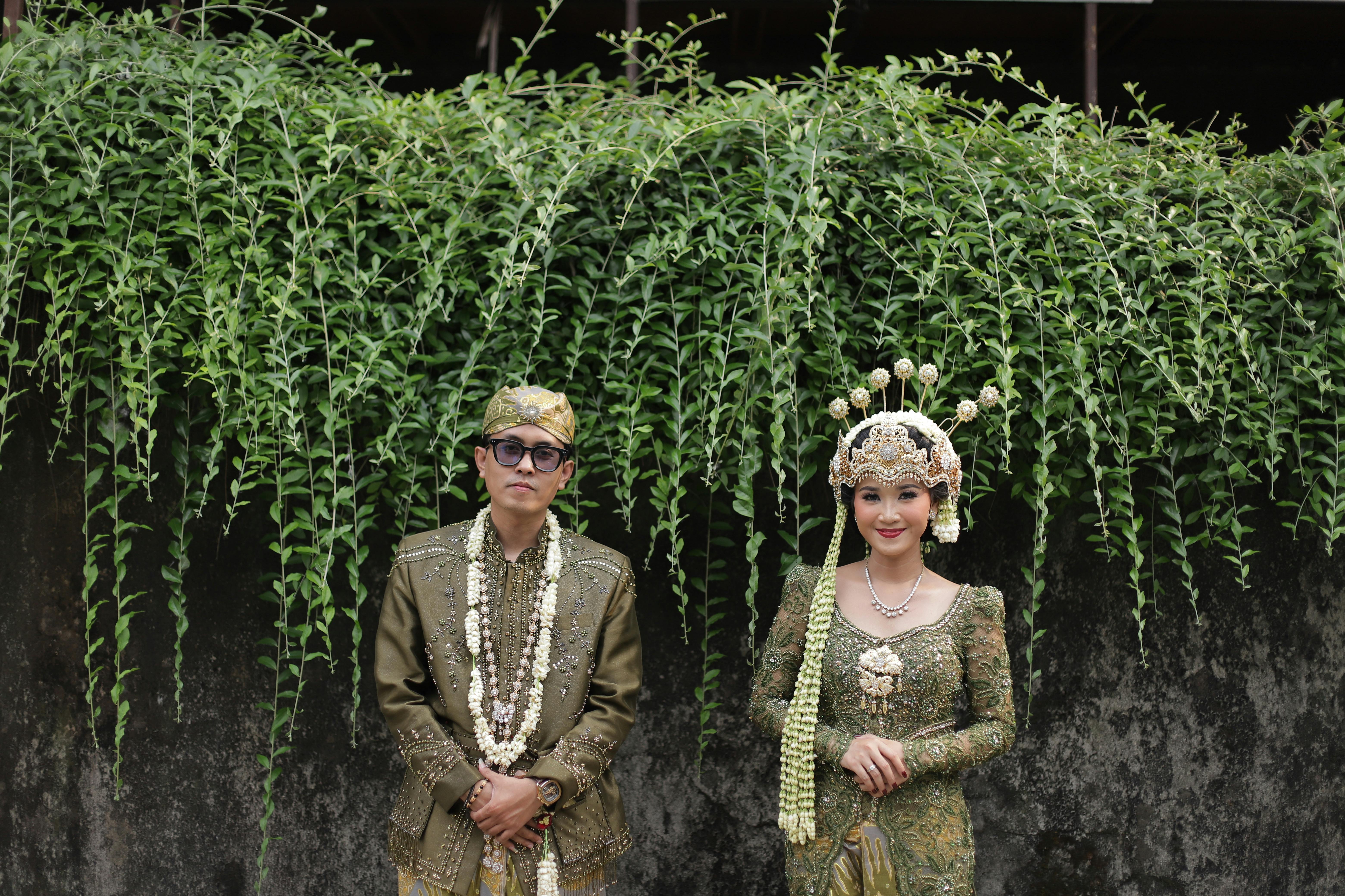 Beautiful portrait of a couple in traditional Indonesian wedding attire captured outdoors.
